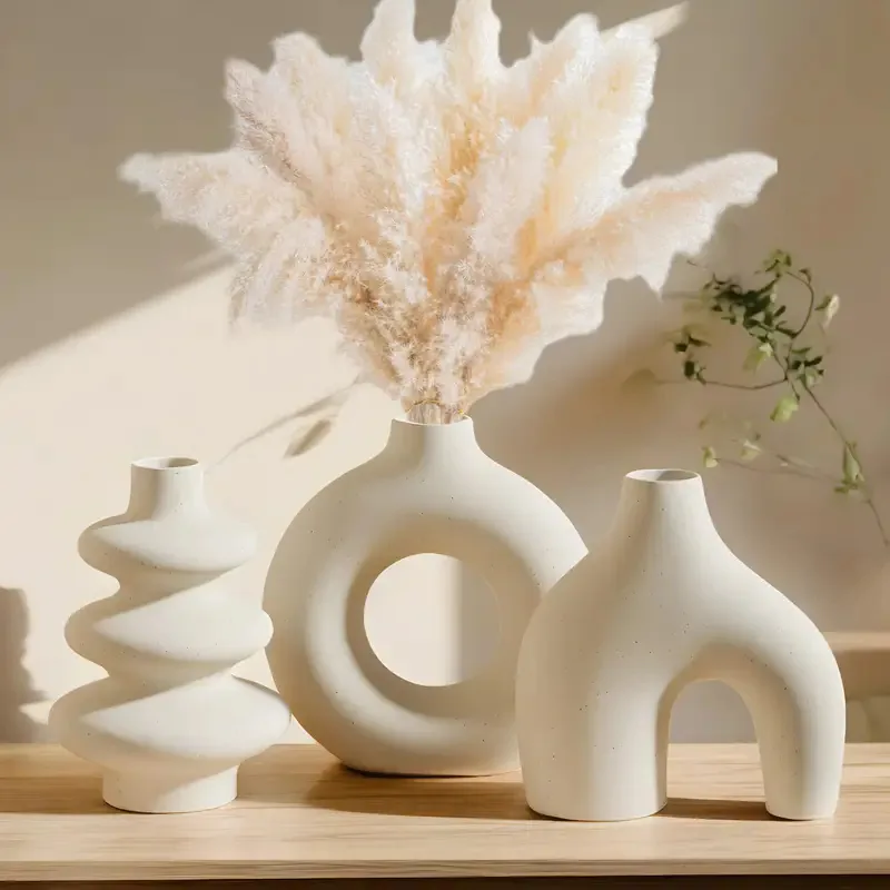 Three sculptural ivory ceramic vases in sunlight