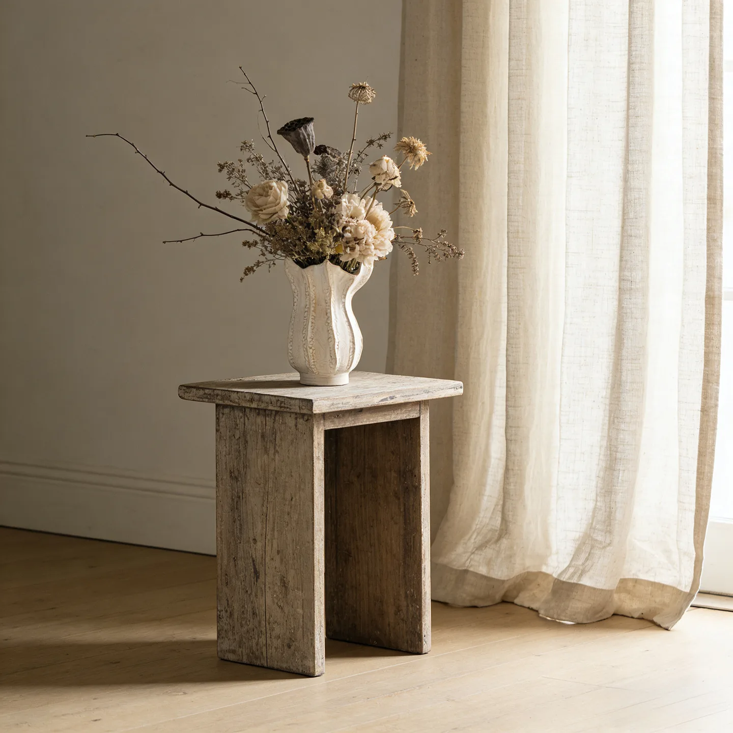 White ceramic vase styled beside a linen curtain
