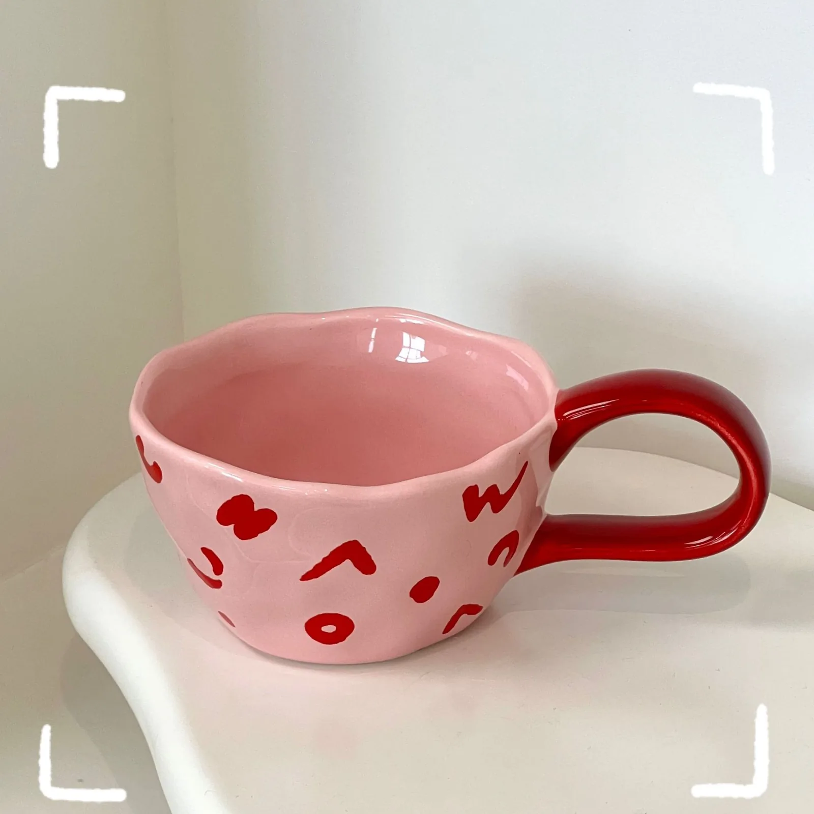 Pink ceramic mug with red abstract illustrations