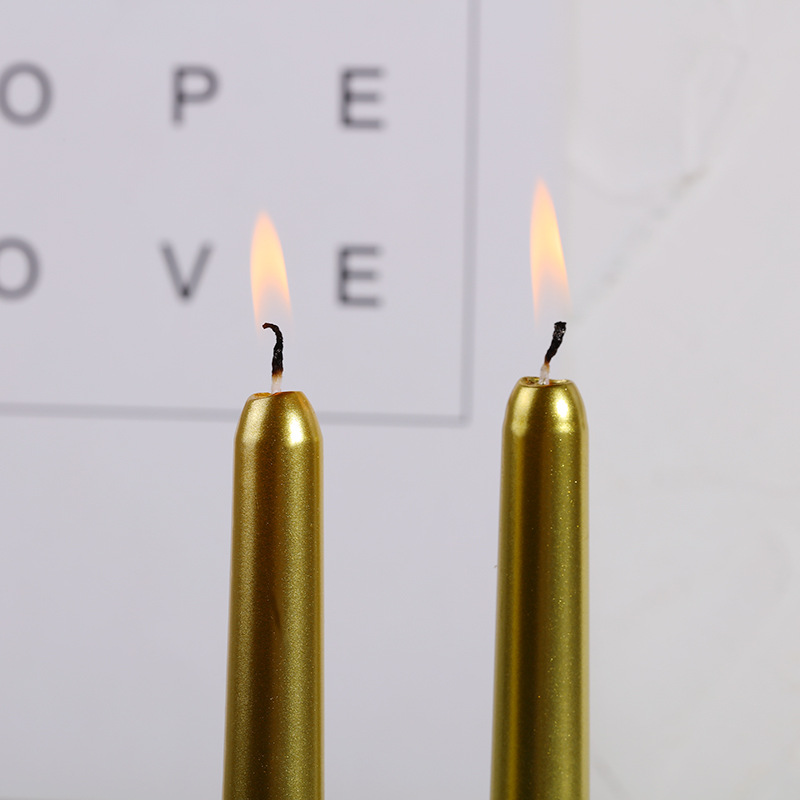 Two burning gold taper candles