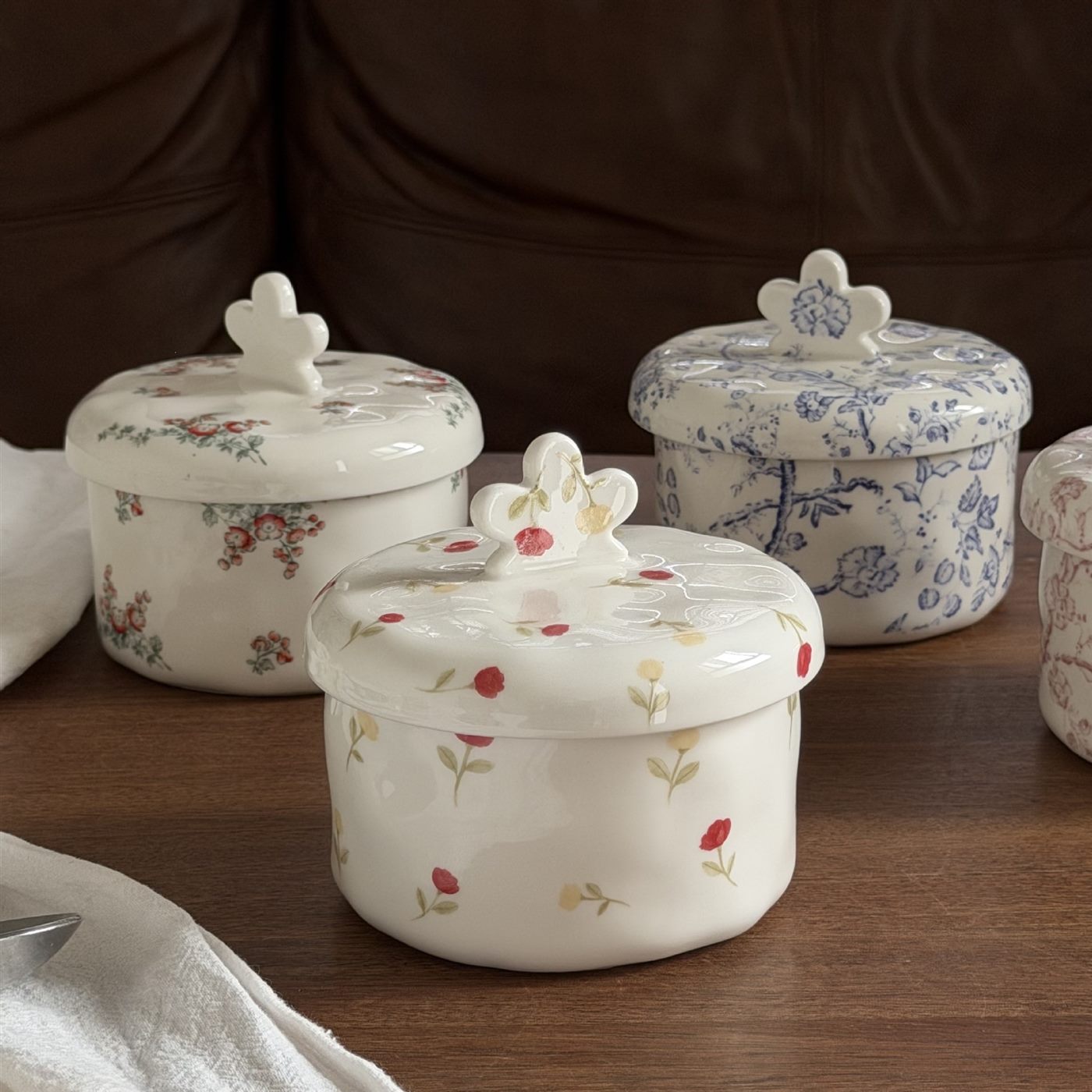 Floral ceramic candy and jewelry boxes displayed on a wooden table