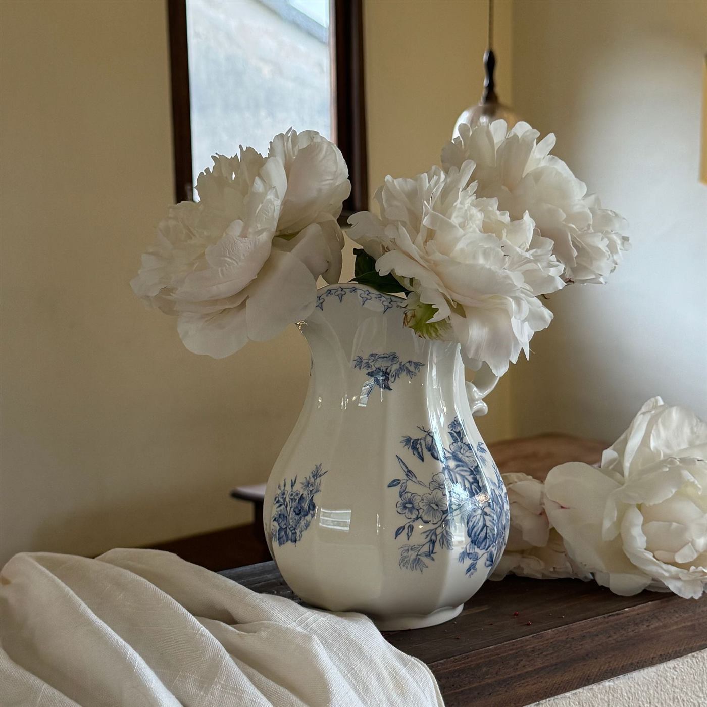Side view of floral ceramic pitcher vase with white flowers