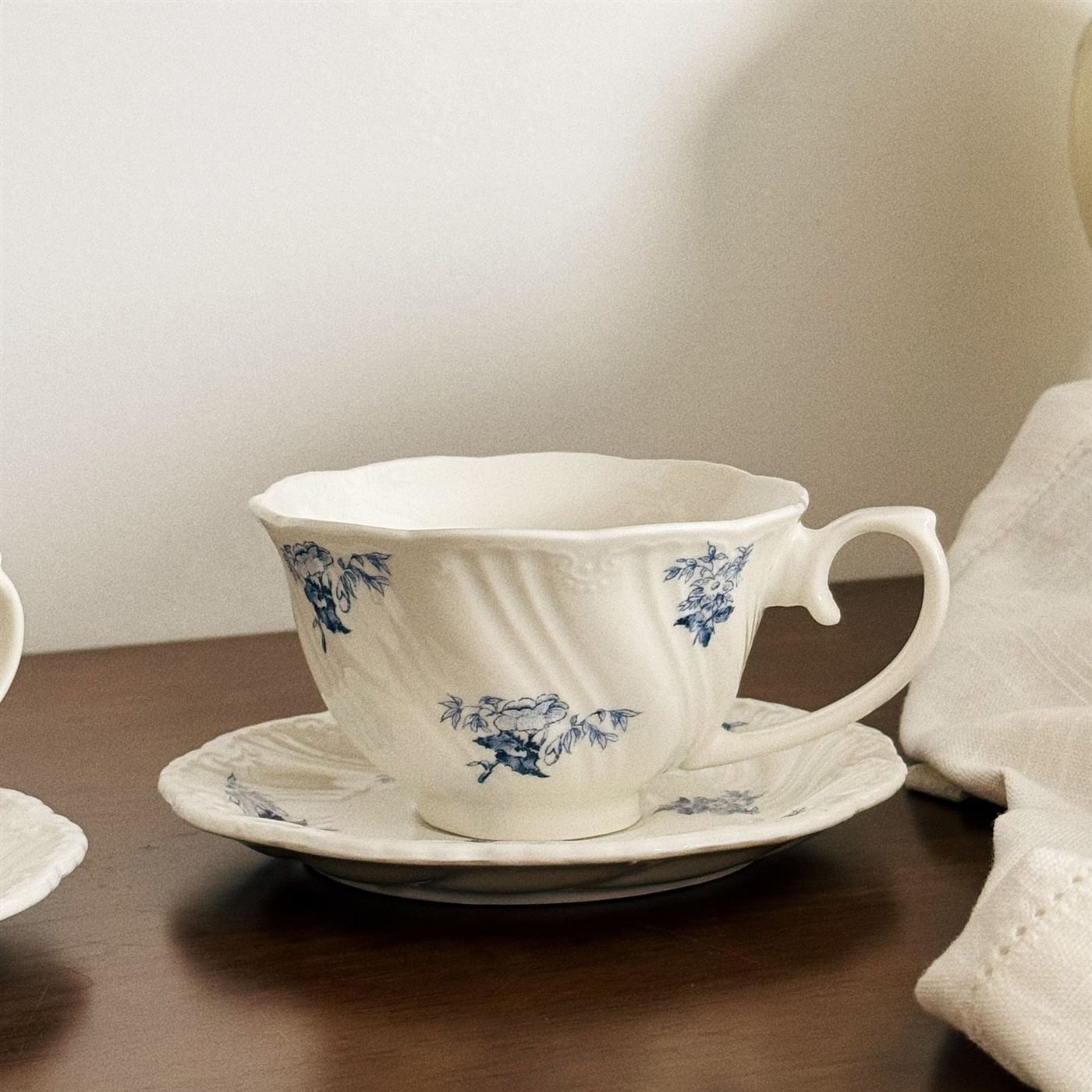 Fluted ceramic coffee cup with scattered blue flowers and saucer