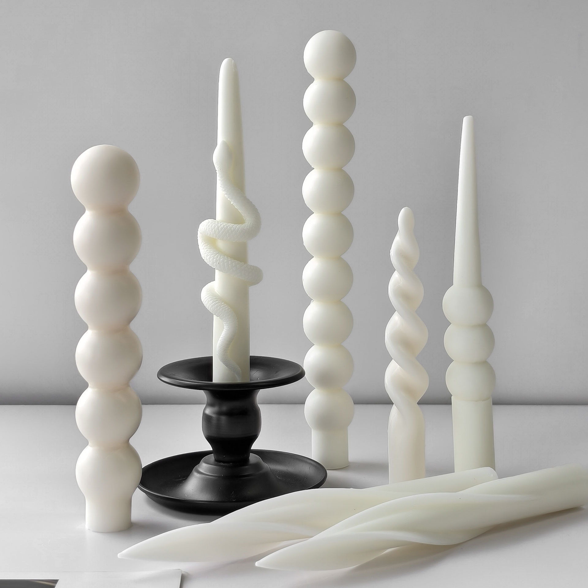 Modern sculptural taper candles displayed with black holders