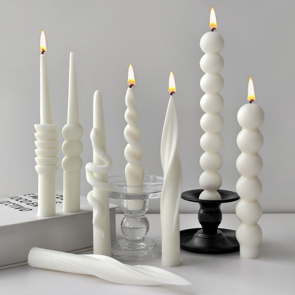 Assorted sculptural taper candles shown lit and unlit