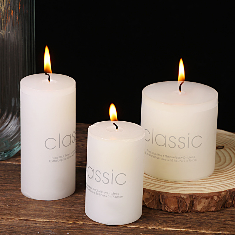 Three burning white paraffin pillar candles