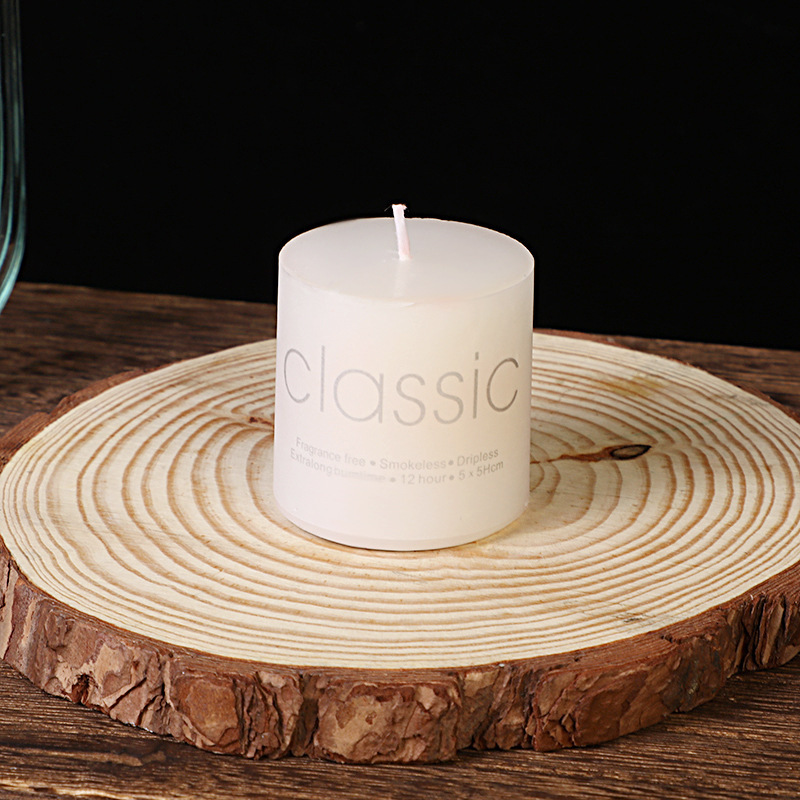 Compact white pillar candle on natural wood slice