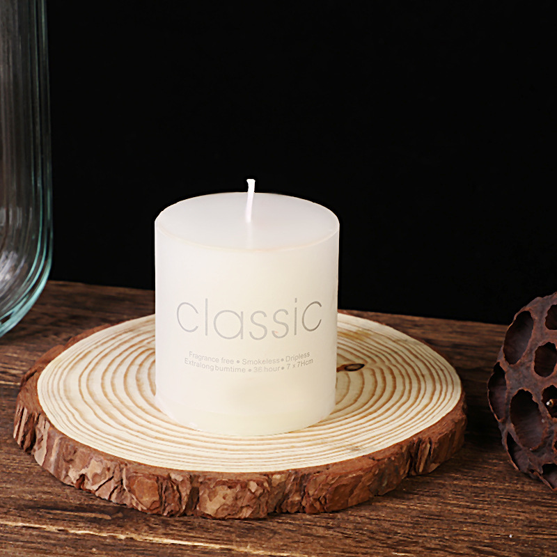 Wide white pillar candle on natural wood slice