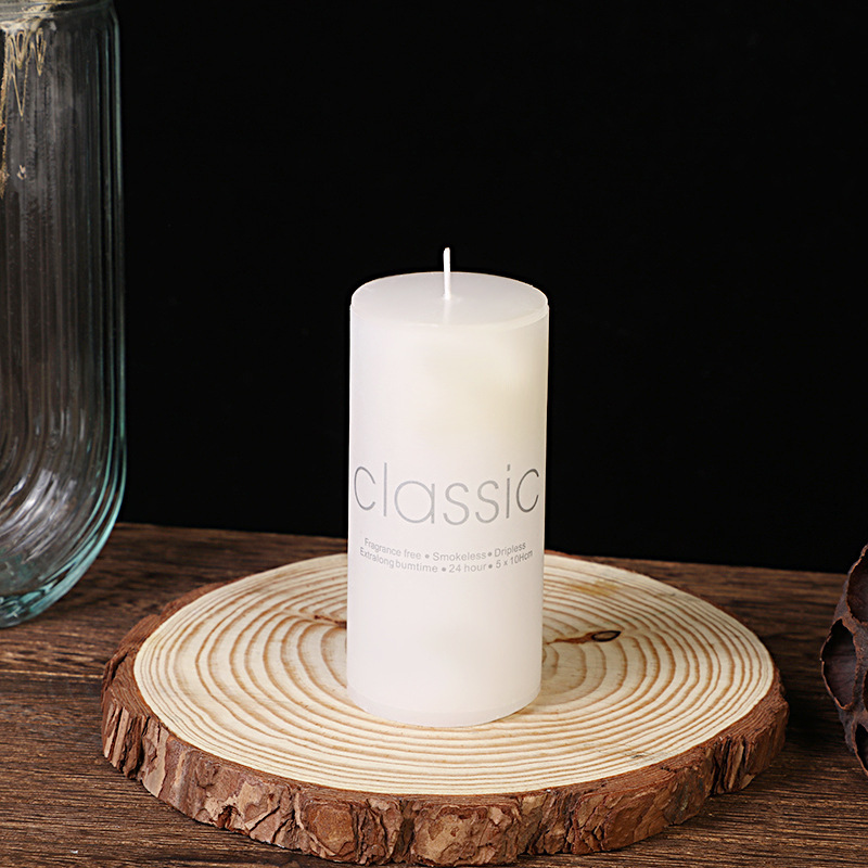 Tall slim white pillar candle on wood slice