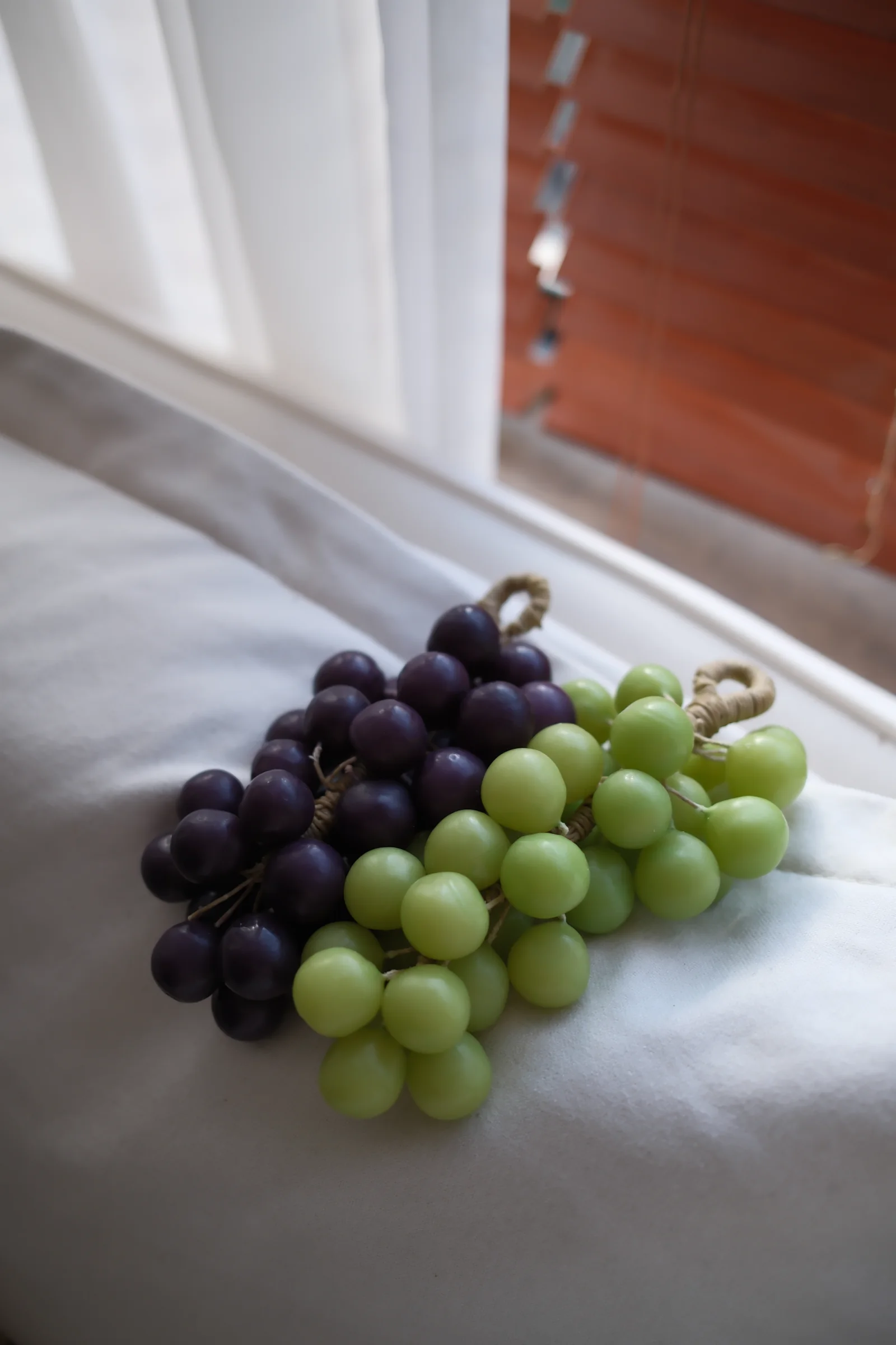 Purple and green grape candles by a window