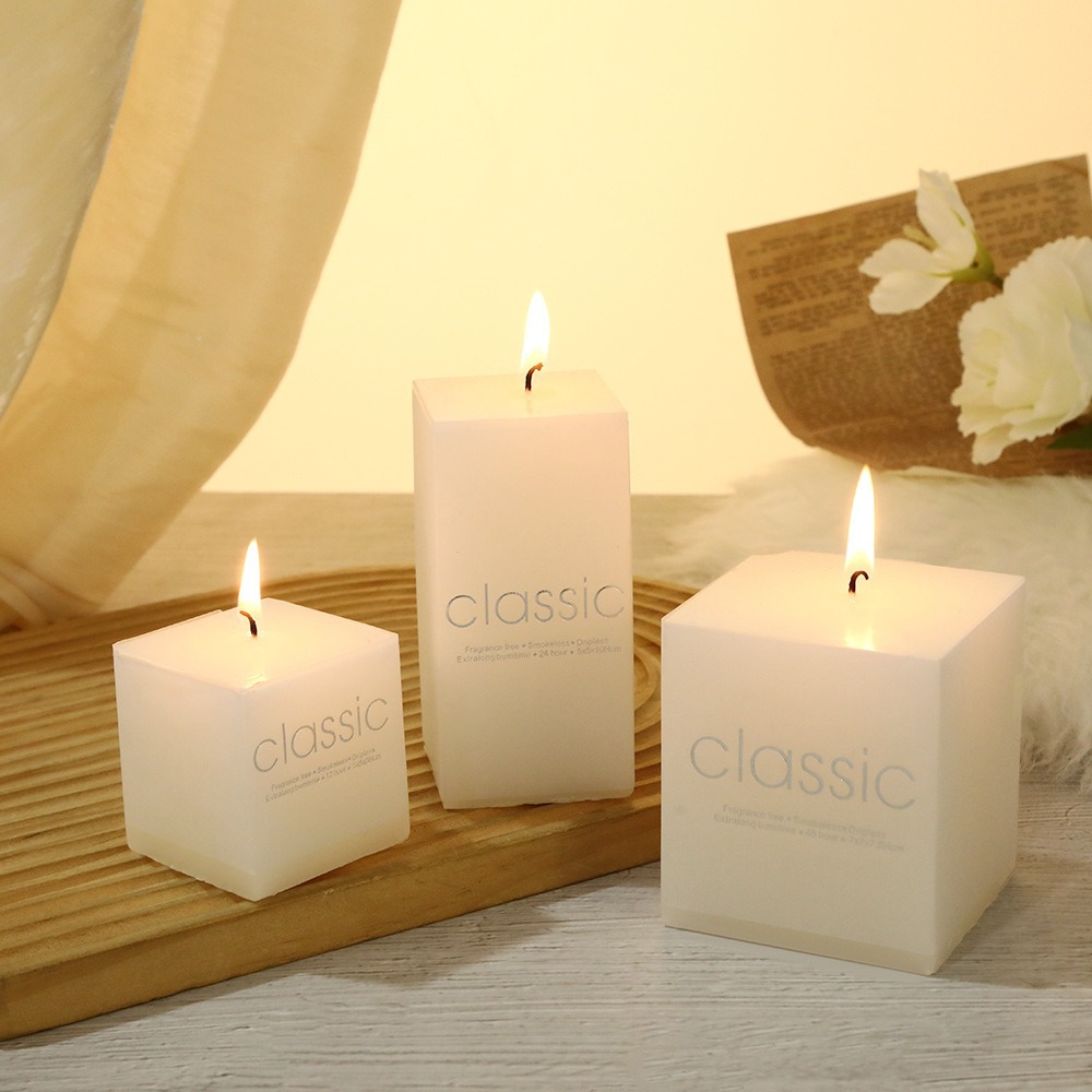Three burning white square pillar candles