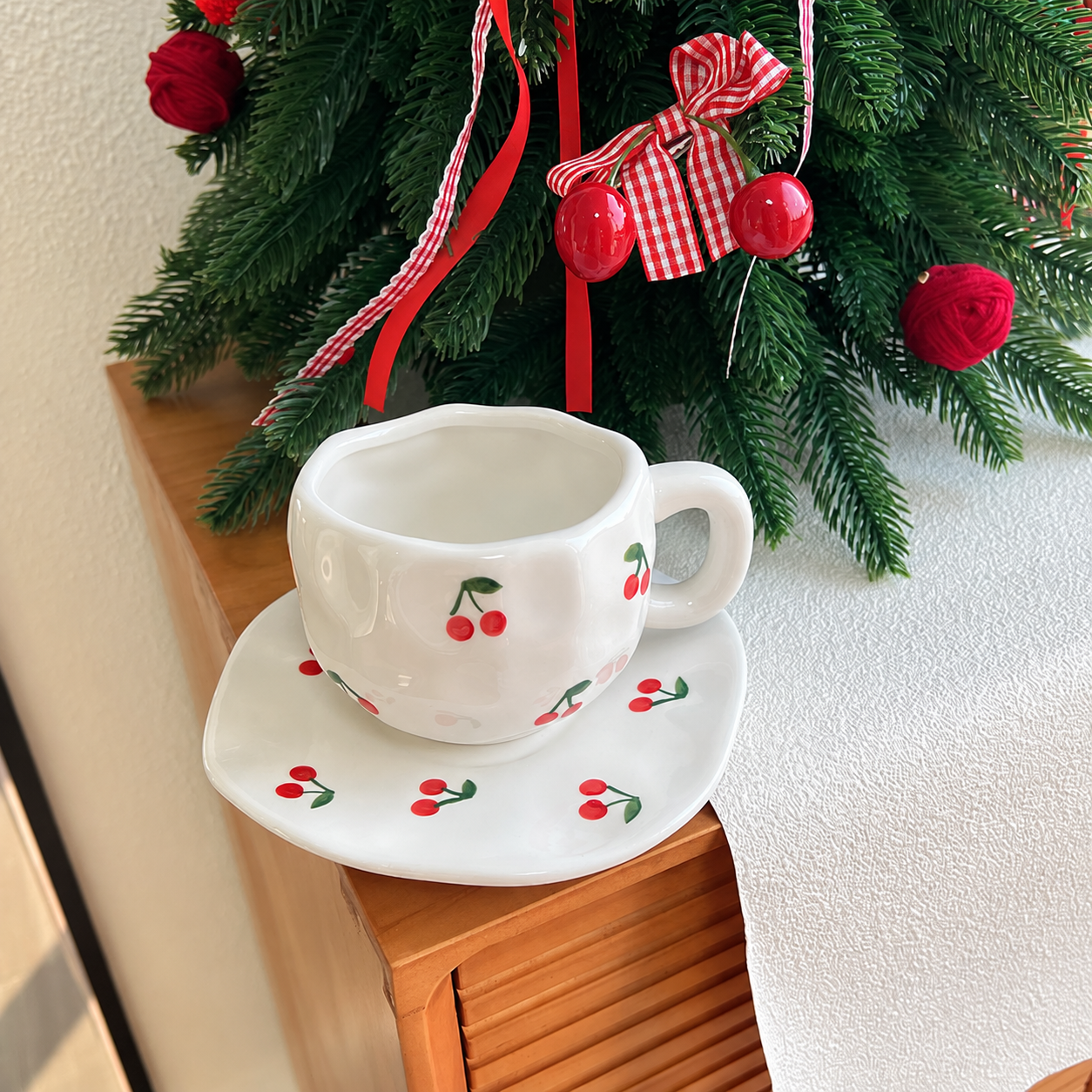 Cherry ceramic cup and saucer set by a Christmas tree