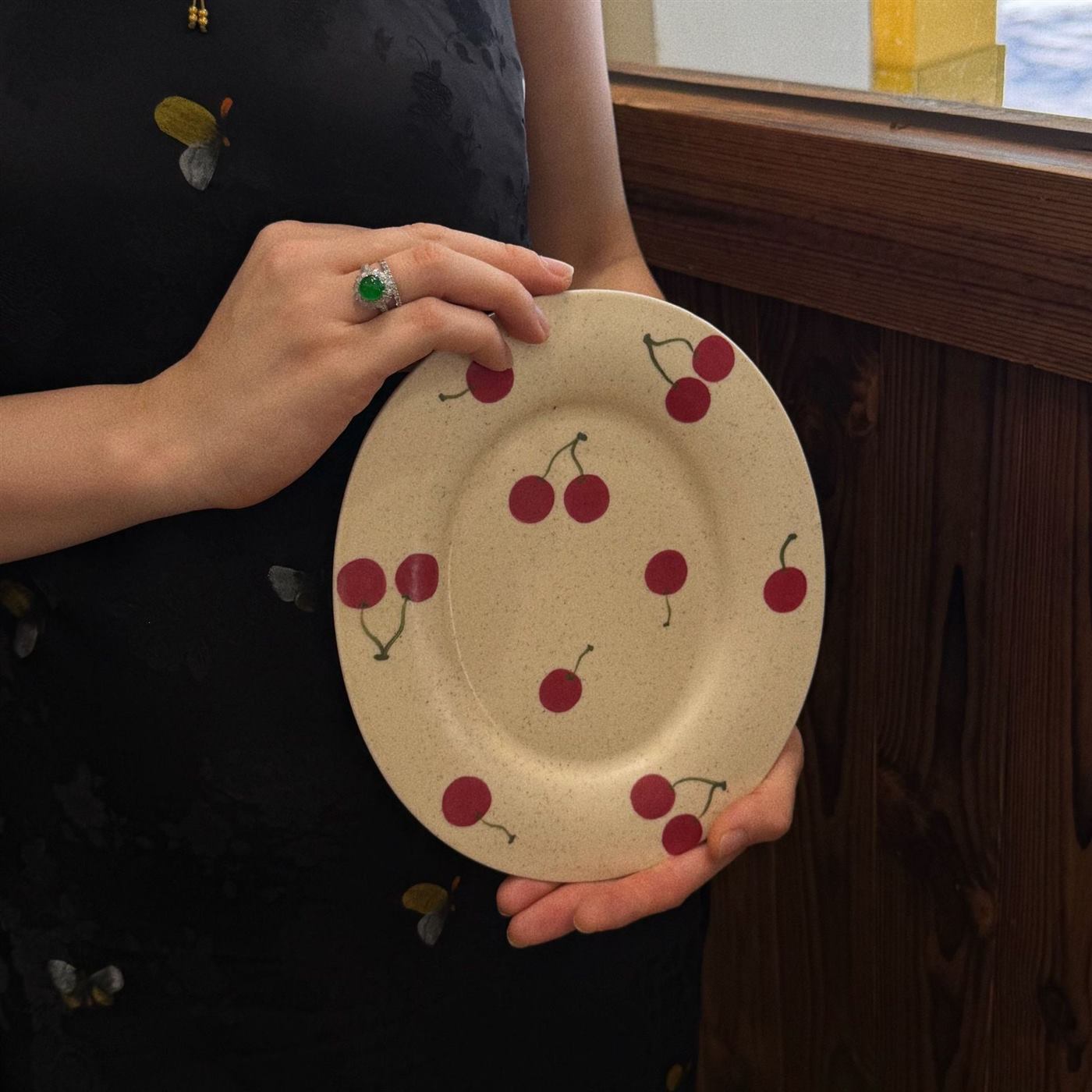 Oval cherry ceramic serving plate held for scale