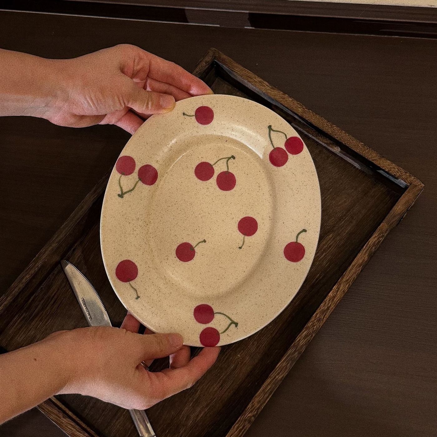 Hand painted cherry ceramic dessert plate on a wooden tray