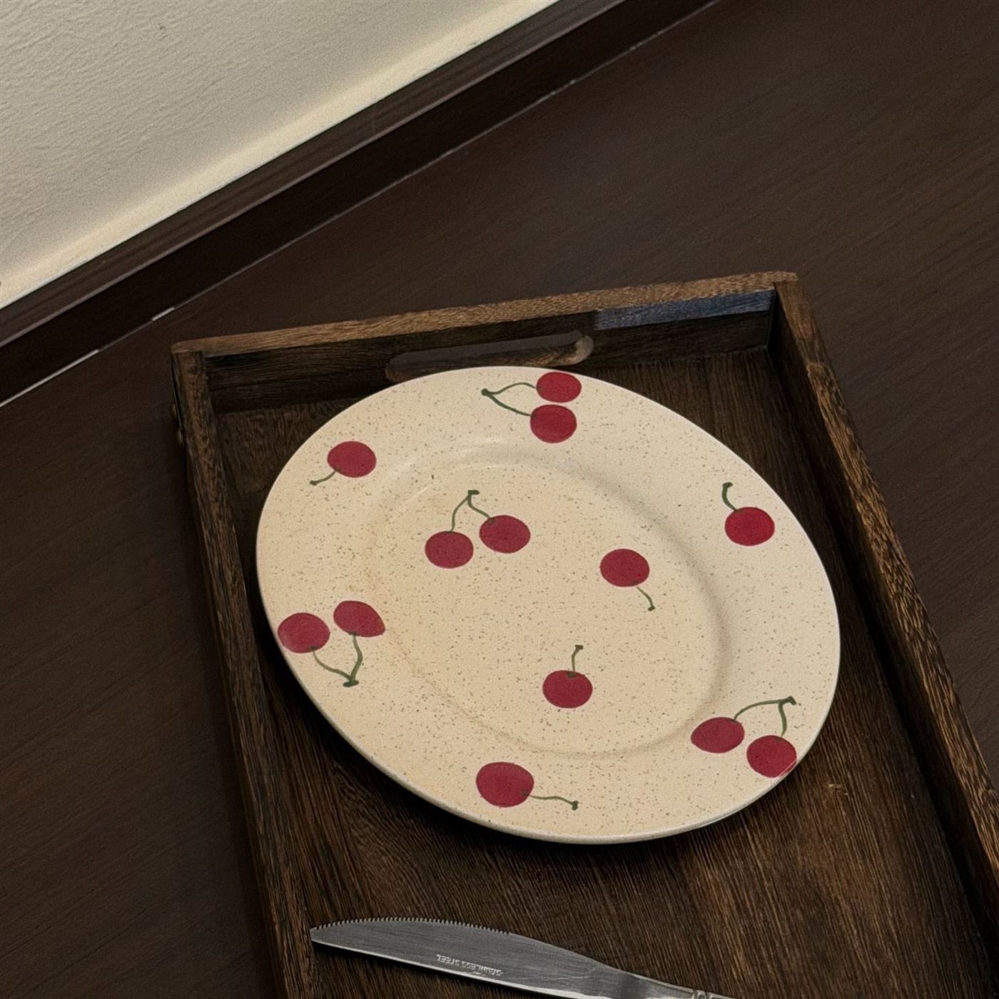 Cherry ceramic plate styled with vintage wooden tableware