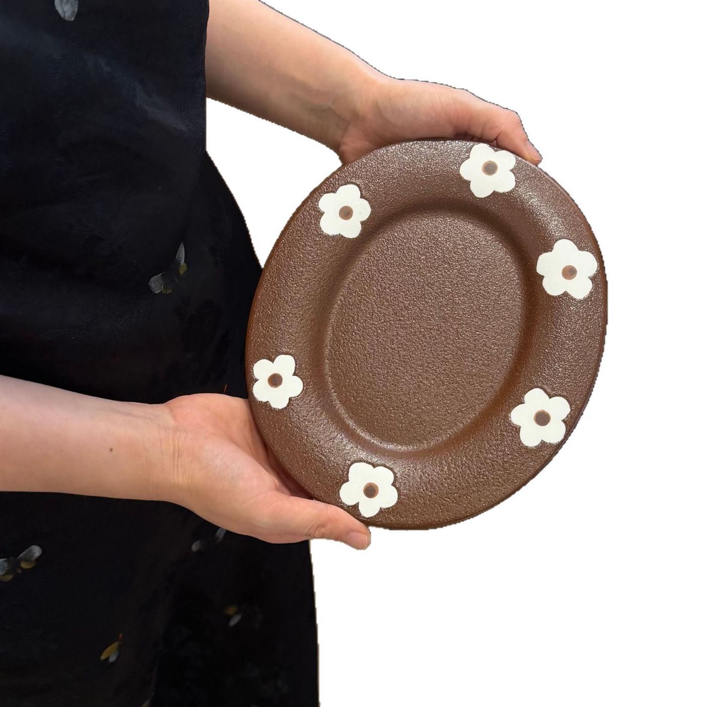 Brown oval matte ceramic plate held for scale