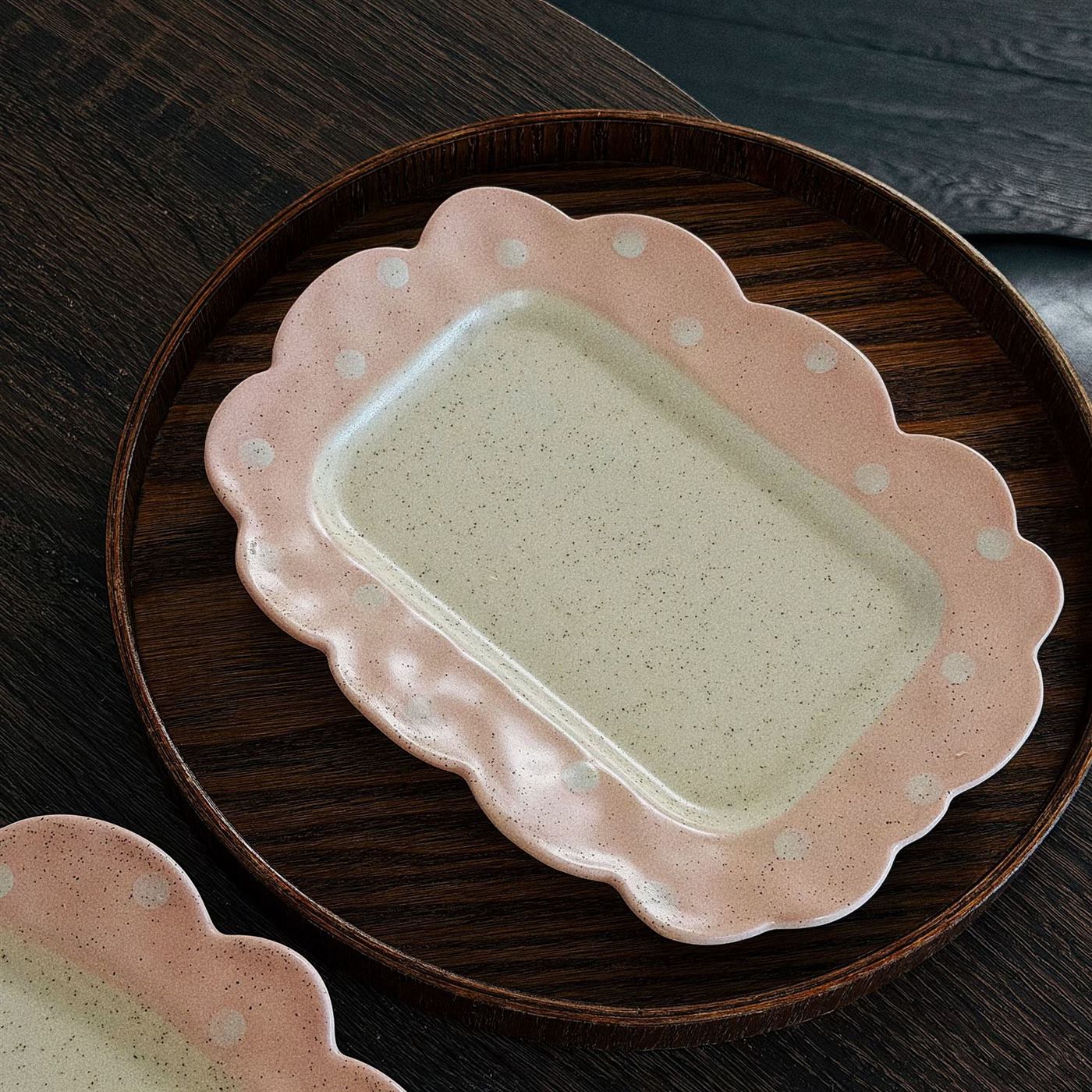 Pink vintage ceramic cake plate displayed on a round wooden tray