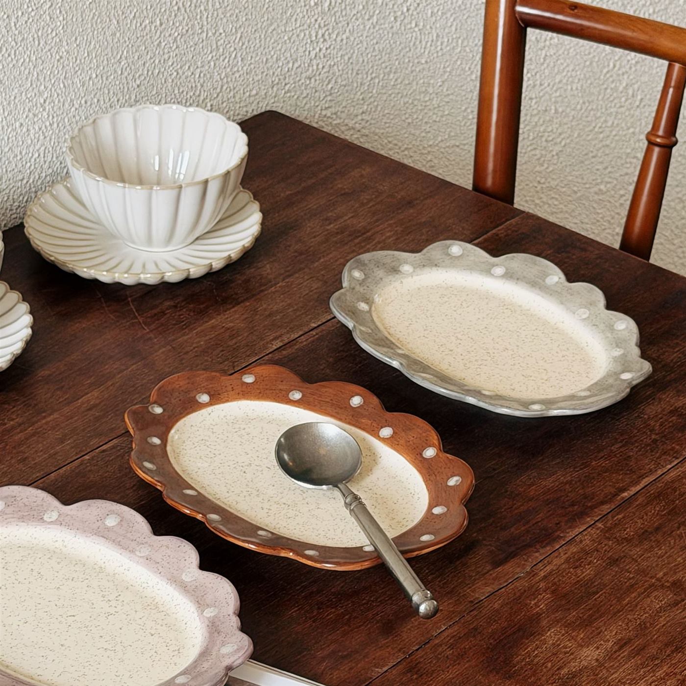 Scalloped ceramic breakfast plates styled on a wooden table