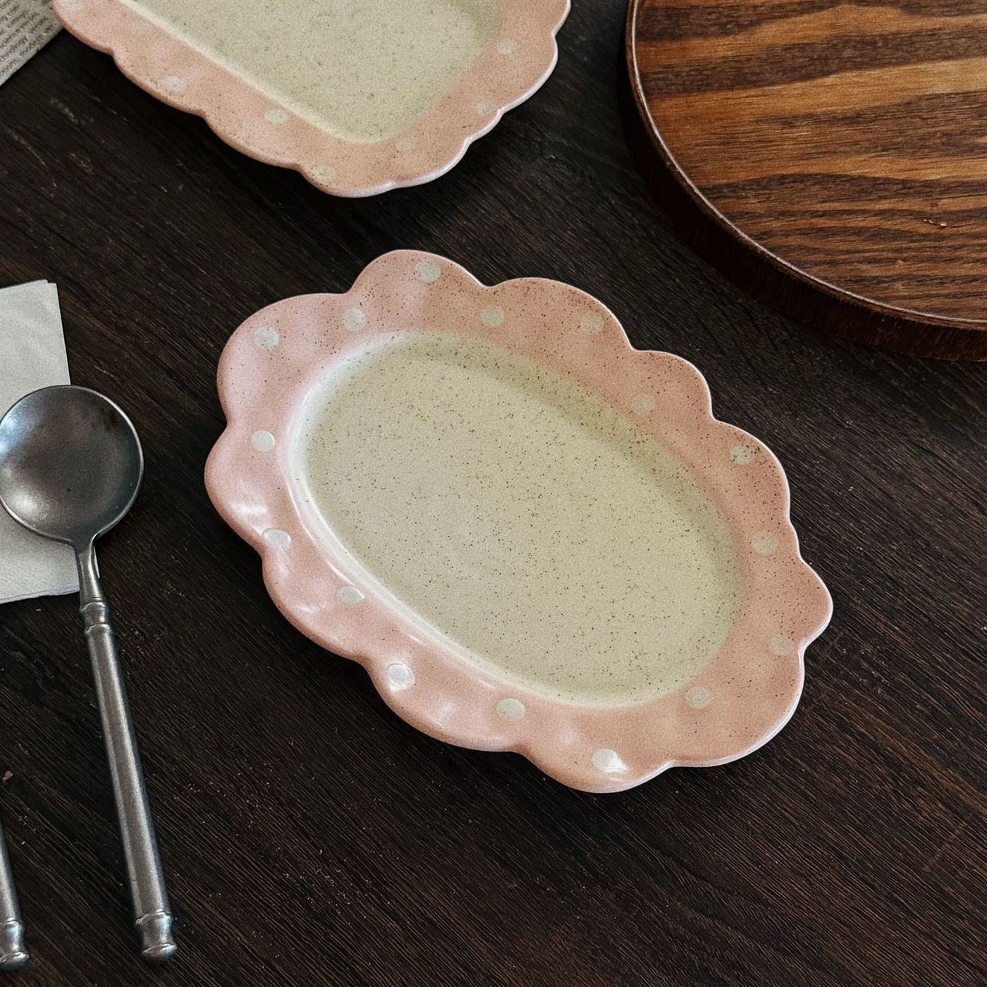 Pink scalloped ceramic breakfast plate on a dark wood table