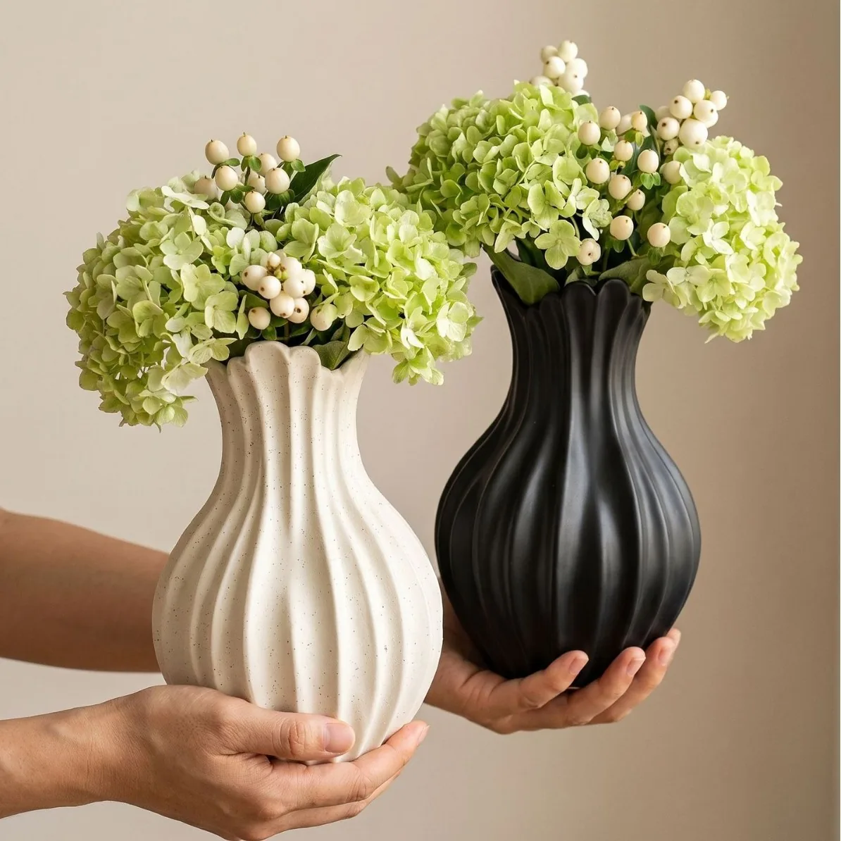 Ivory and black sculptural ceramic vases held side by side