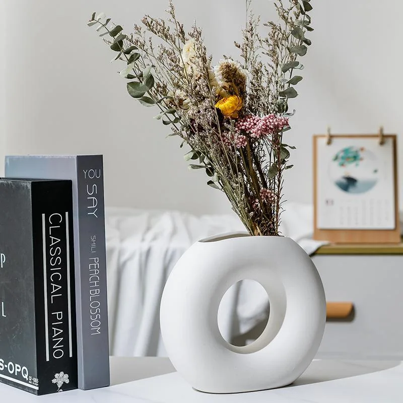 White ring ceramic flower vase beside decorative books